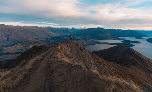 Hiker standing on mountain against sky