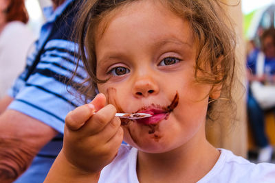 Close-up portrait of cute girl eating chocolate