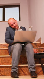 Man using laptop while sitting on sofa at home