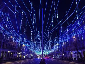 Light trails on road against blue sky at night