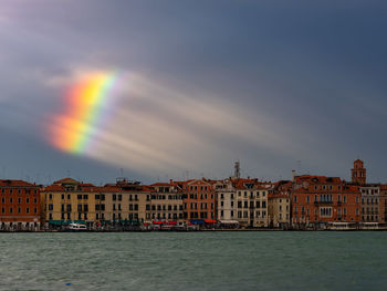 Scenic view of rainbow over buildings in city against sky