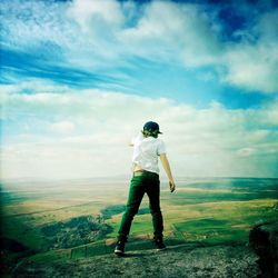 Man standing on grass against cloudy sky