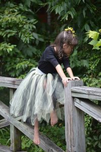 Girl sitting on wooden railing at park