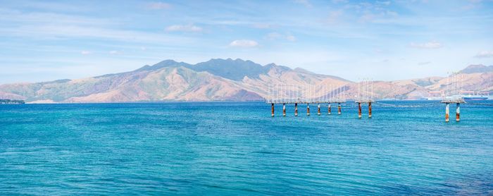 Scenic view of sea and mountains against blue sky