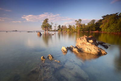 Rocks by lake against sky