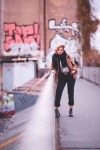 Portrait of smiling young woman standing against wall