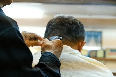 Close-up of barber trimming hair of customer