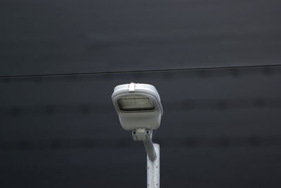 Low angle view of electric lamp against building 