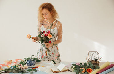 Young woman looking at camera on table against wall