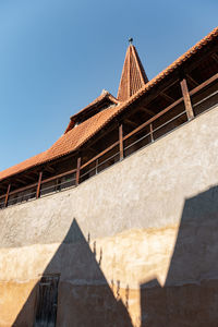 Low angle view of  medieval building  with shadow on the  city wall against blue sky