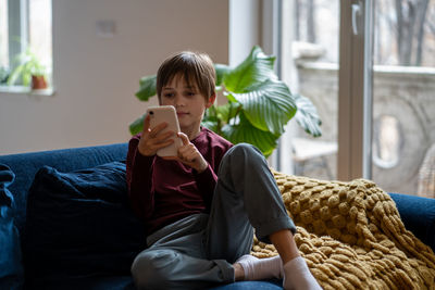 Portrait of young woman sitting on sofa at home