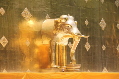 Golden elephant statue against wall