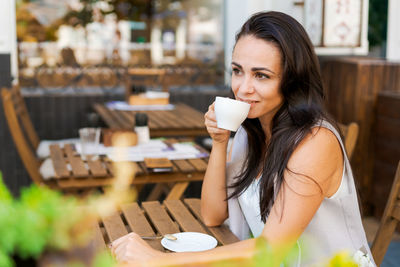 Happy smiling business brunette drinking coffee in a street cafe. coffee break