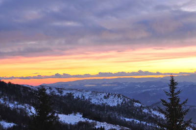 Scenic view of snow covered mountains against sky at sunset