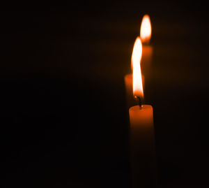 Close-up of lit candle in darkroom