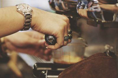 Cropped hand of woman filling cup with coffee in cafe