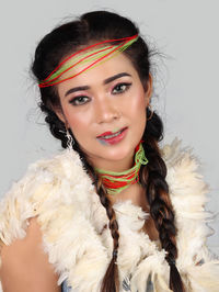 Portrait of young woman wearing fur coat against white background