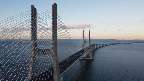 Bridge over sea against sky during sunset