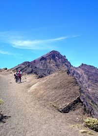 People on mountain against blue sky