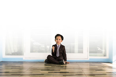 Full length of boy sitting on tiled floor