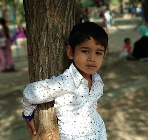 Portrait of cute girl against tree trunk