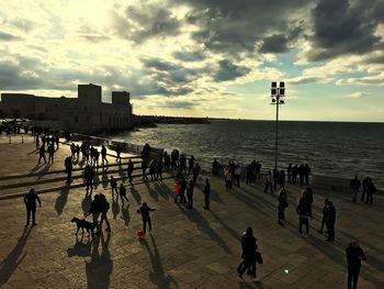 People on beach against sky during sunset