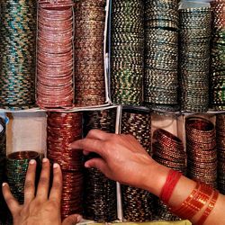 Cropped hands choosing bangles in shelf