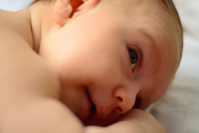 Close-up portrait of cute baby lying on bed