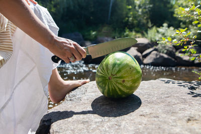 Low section of woman cutting watermelon outdoors