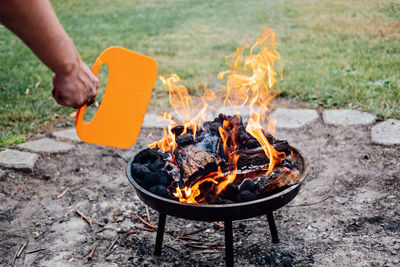 How to use a charcoal grill. man with plastic bbq hand fan near charcoal grill fire. barbeque