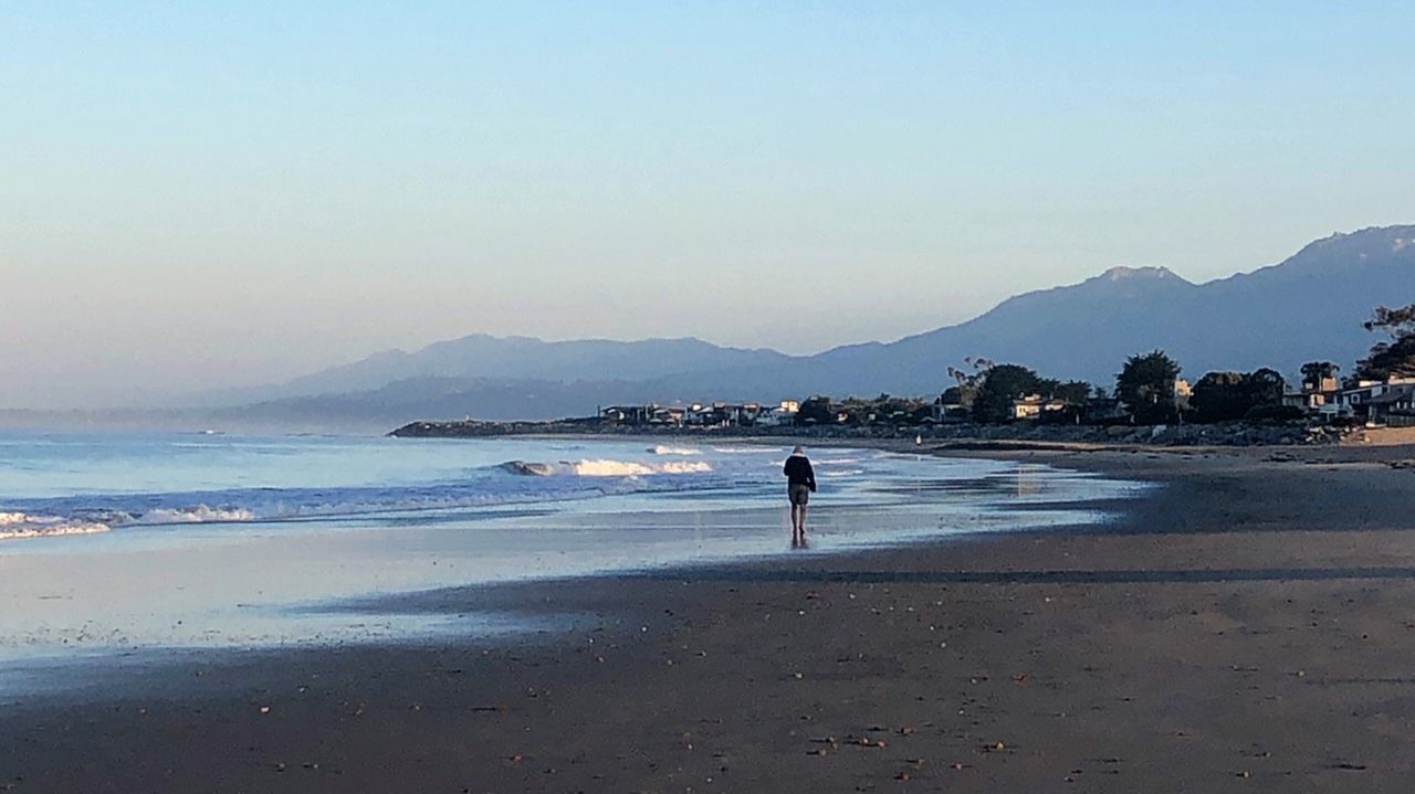 PEOPLE ON BEACH BY SEA AGAINST SKY