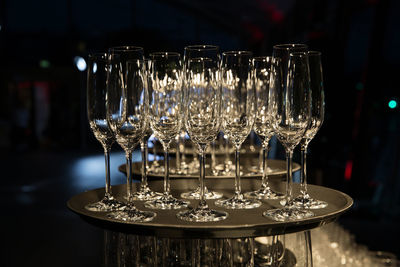 Empty collection of champagne cups on tray in dark room.