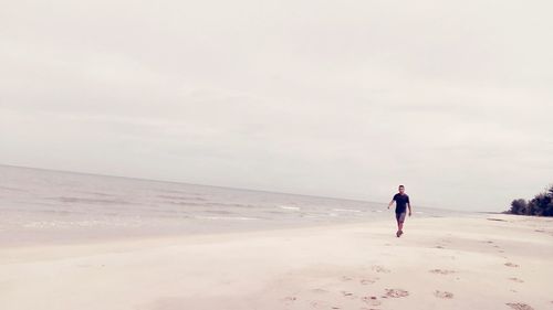 Rear view of man on beach against sky