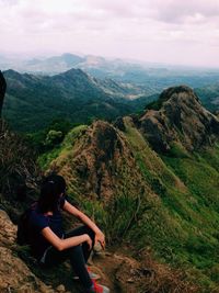 Rear view of woman sitting on grassy landscape