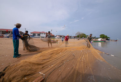 People working at beach against sky