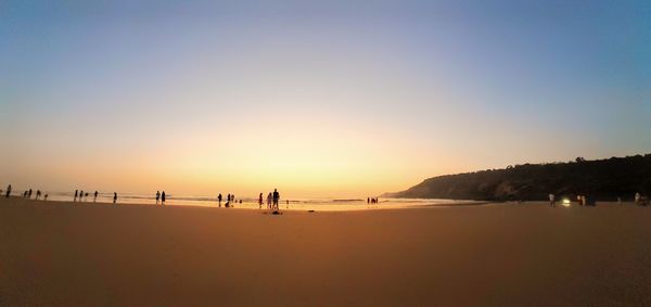 Scenic view of beach against clear sky during sunset