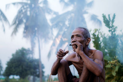 Old man are smoking in the countryside on field.