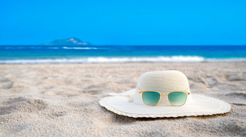 Sunglasses on sand at beach against blue sky