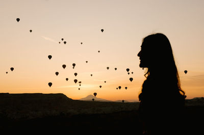 Silhouette woman standing against orange sky during sunset