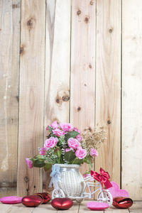 Flower vase with heart shape decorations by wooden wall