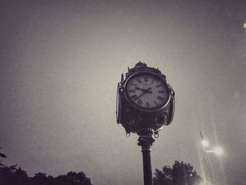 Low angle view of clock on street light against sky