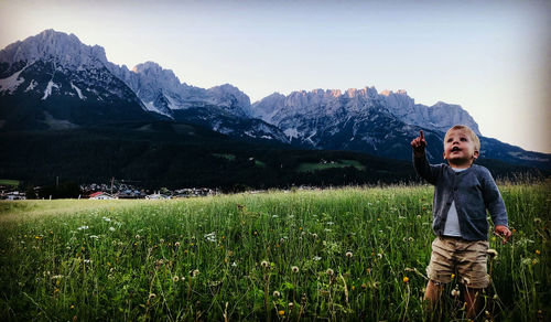 Boy standing by plants against sky