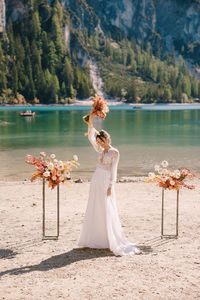 Woman with umbrella by lake against trees