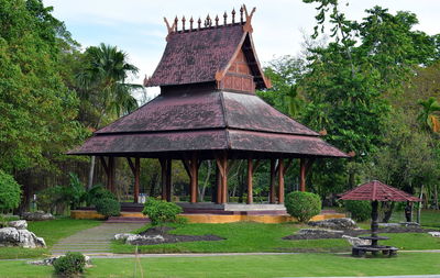 Gazebo in lawn by building against sky