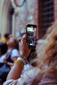 A tourist taking a picture at a packed courtyard of juliet's house im verona, italy 