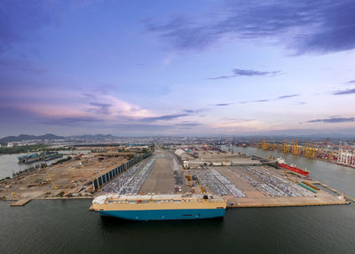 Aerial logistics commercial vehicles waiting to be load on to a car carrier ship at dockyard