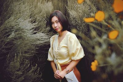 Beautiful young woman standing against plants