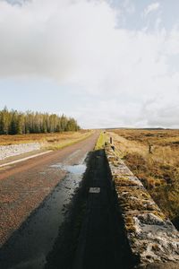 Road amidst field against sky