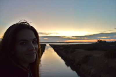 Portrait of woman smiling against sky during sunset