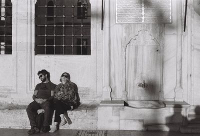 Couple sitting on window of building